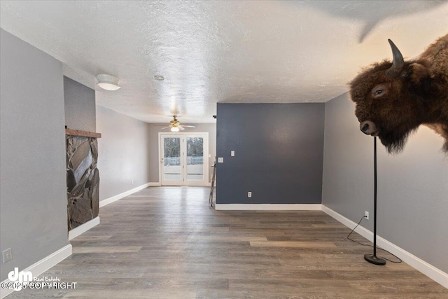 unfurnished living room featuring dark hardwood / wood-style flooring, ceiling fan, a fireplace, and a textured ceiling