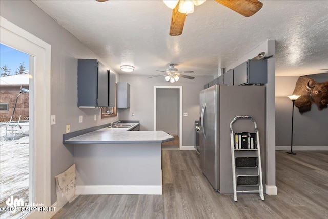 kitchen featuring dark hardwood / wood-style floors, sink, stainless steel fridge, kitchen peninsula, and a textured ceiling