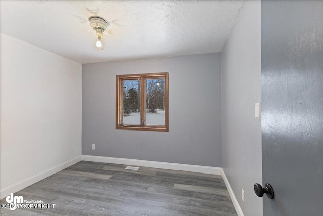 spare room with dark wood-type flooring and a textured ceiling