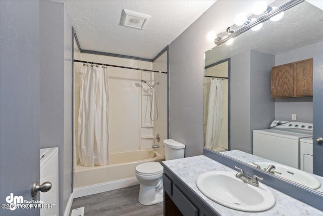 full bathroom featuring washer and dryer, a textured ceiling, hardwood / wood-style flooring, vanity, and shower / bath combination with curtain