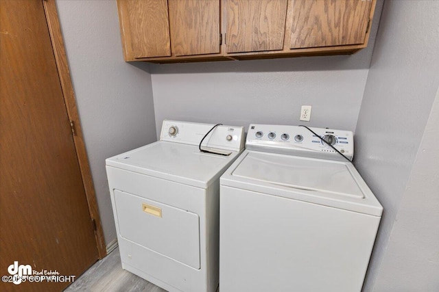 laundry room featuring light hardwood / wood-style flooring, washer and clothes dryer, and cabinets