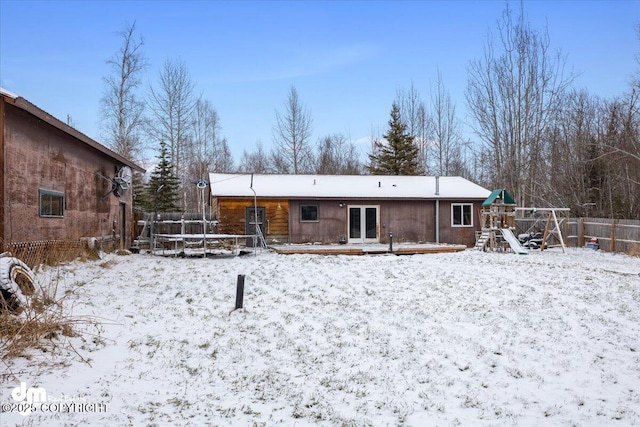 snow covered house featuring a playground and a trampoline