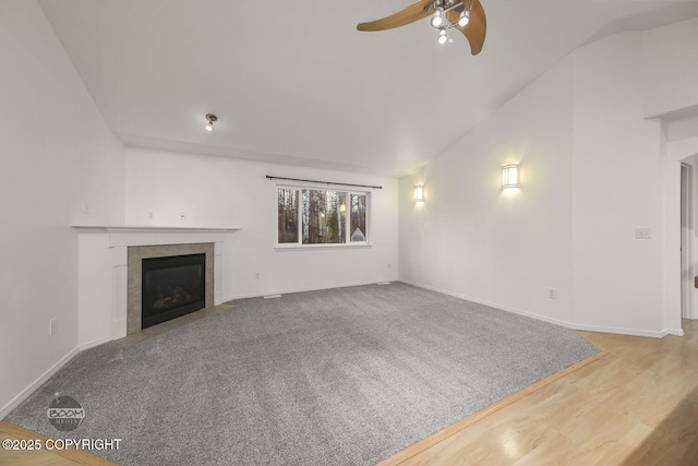 unfurnished living room with ceiling fan, wood-type flooring, lofted ceiling, and a tiled fireplace