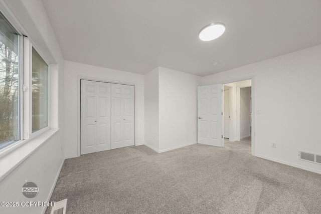 unfurnished bedroom featuring light colored carpet and a closet