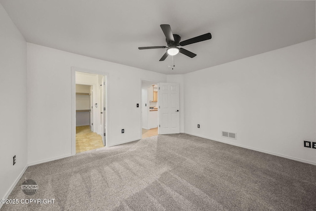 unfurnished bedroom with a walk in closet, ceiling fan, light carpet, and a closet