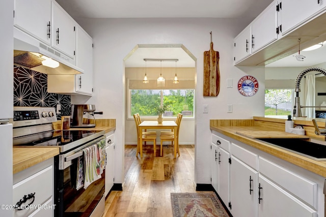 4800 Folker St, Anchorage, AK 99507 - kitchen featuring stainless steel electric range oven, a sink, under cabinet range hood, light wood finished floors, and white cabinets