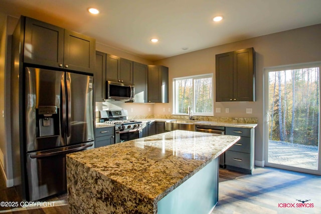 kitchen with stainless steel appliances, a healthy amount of sunlight, a center island, and sink