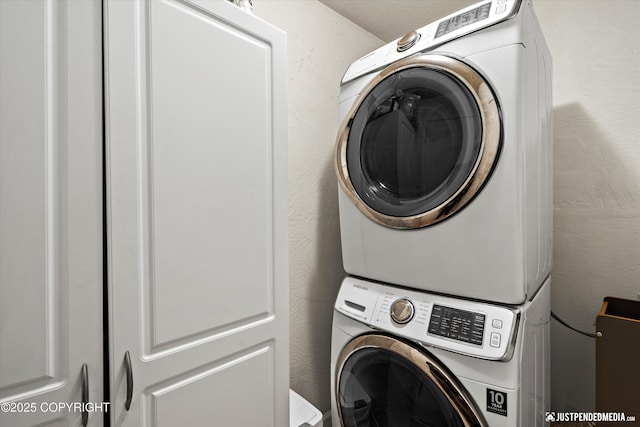 washroom featuring a textured wall, stacked washer and dryer, and laundry area