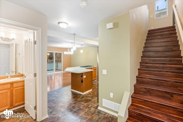 staircase with an inviting chandelier, wood-type flooring, and sink