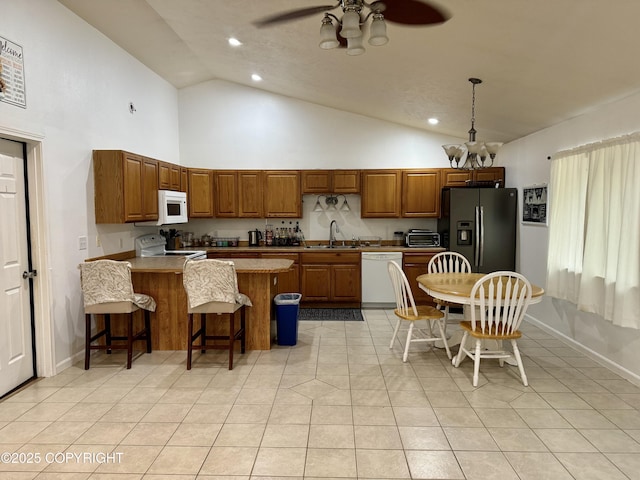 kitchen featuring a breakfast bar, sink, light tile patterned floors, pendant lighting, and white appliances