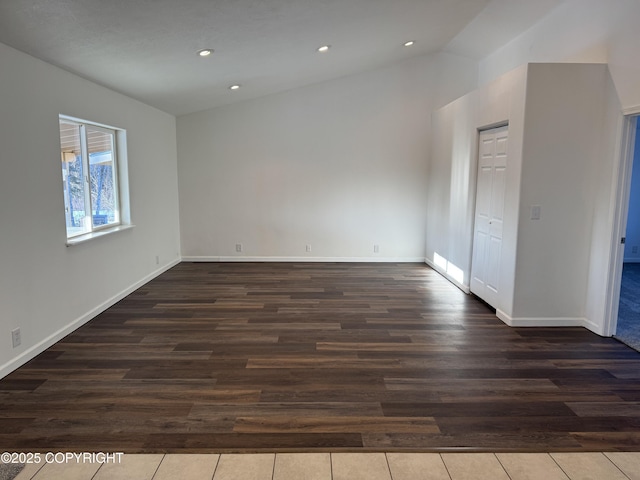 empty room featuring vaulted ceiling and dark wood-type flooring