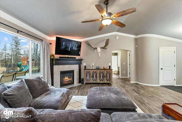 living room featuring lofted ceiling, crown molding, ceiling fan, hardwood / wood-style floors, and a tiled fireplace