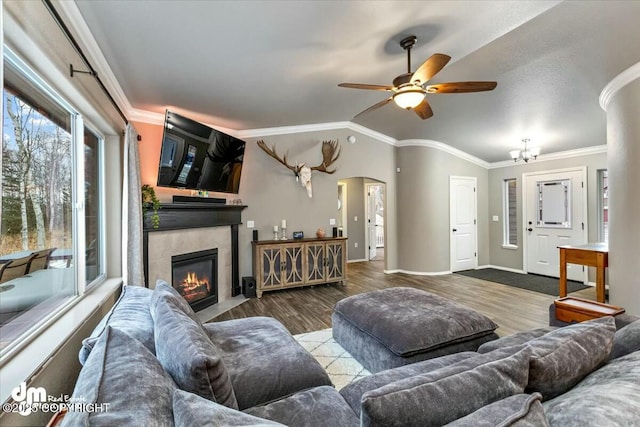 living room featuring hardwood / wood-style floors, vaulted ceiling, ornamental molding, and a fireplace