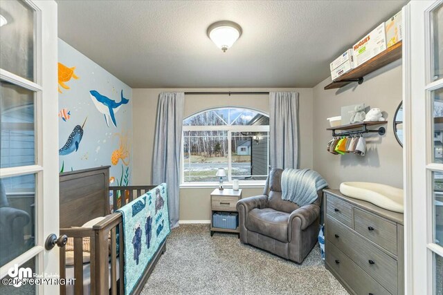 carpeted bedroom featuring a crib and a textured ceiling