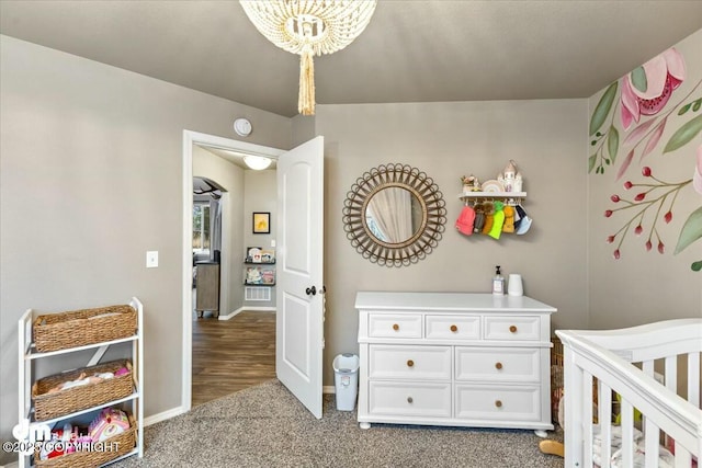 bedroom with a notable chandelier, a nursery area, and carpet