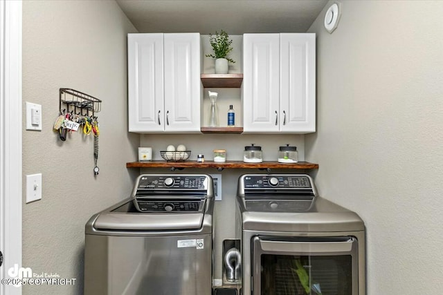 clothes washing area featuring cabinets and washer and clothes dryer