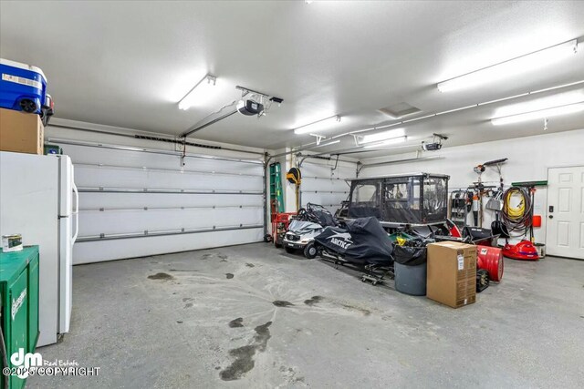 garage with a garage door opener and white fridge