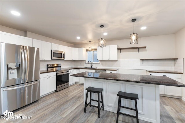 kitchen featuring sink, appliances with stainless steel finishes, a kitchen island, light hardwood / wood-style floors, and white cabinets