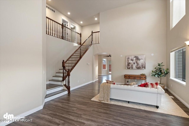 living room featuring a healthy amount of sunlight, dark hardwood / wood-style flooring, and a high ceiling