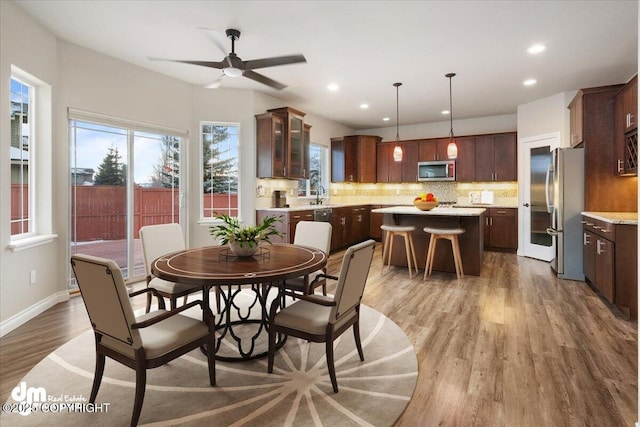 dining area with hardwood / wood-style flooring, ceiling fan, and sink