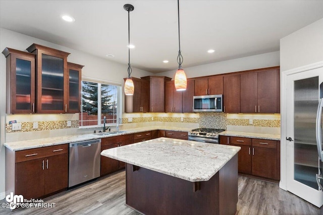 kitchen with stainless steel appliances, decorative light fixtures, a center island, backsplash, and sink