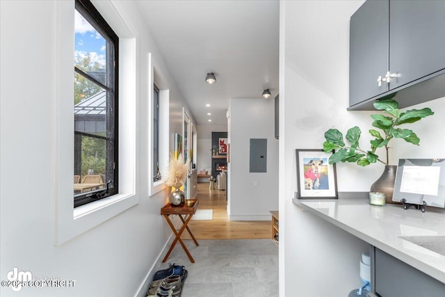 hall with a wealth of natural light, electric panel, and a chandelier