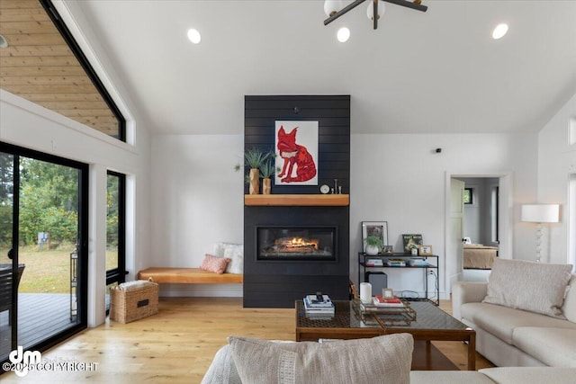 living room with a fireplace, vaulted ceiling, and light hardwood / wood-style flooring