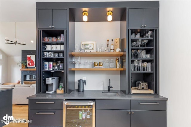 bar featuring wine cooler, sink, light hardwood / wood-style flooring, and gray cabinetry