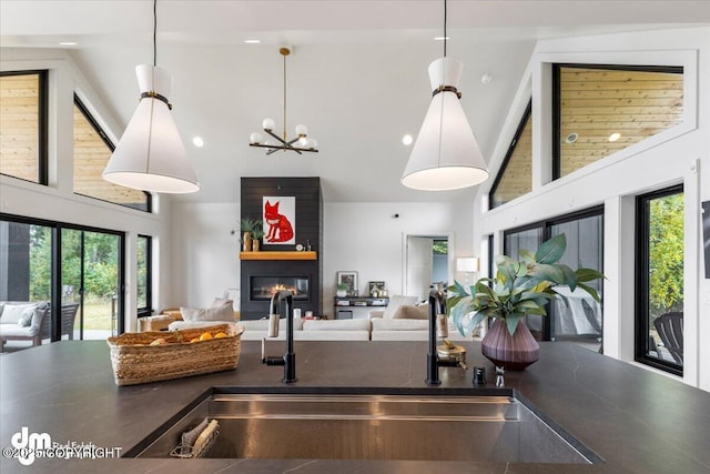 kitchen featuring sink, decorative light fixtures, a fireplace, and high vaulted ceiling