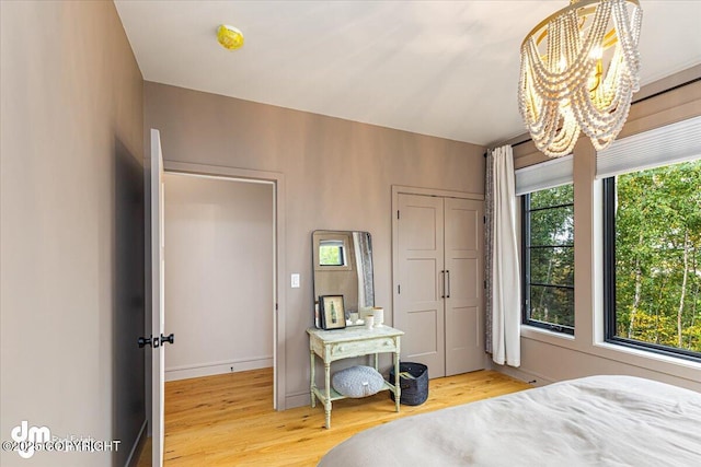 bedroom featuring an inviting chandelier, light hardwood / wood-style floors, and multiple windows