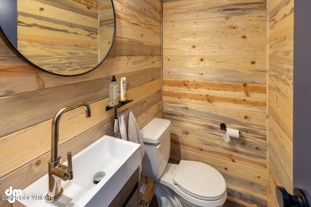 bathroom with vanity, toilet, and wood walls