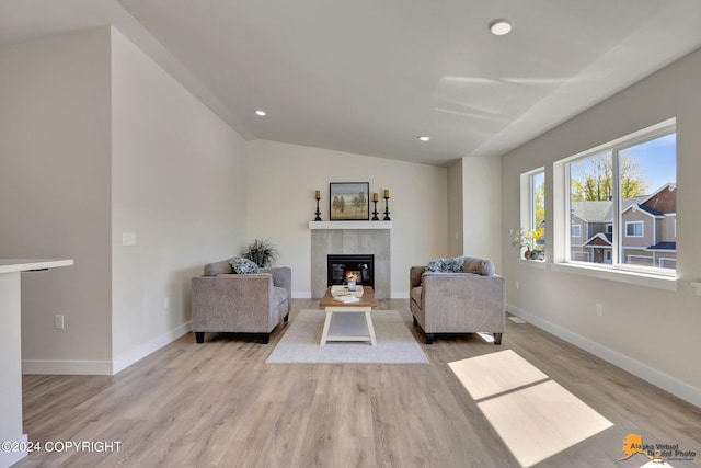 living room featuring a fireplace, light hardwood / wood-style flooring, and vaulted ceiling