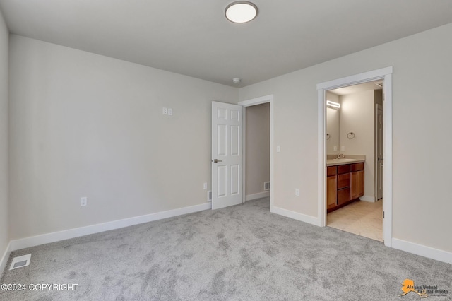 unfurnished bedroom featuring connected bathroom and light colored carpet