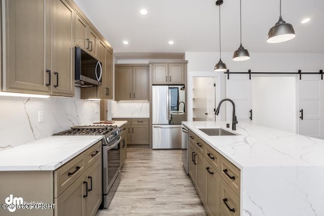 kitchen with pendant lighting, sink, a large island, stainless steel appliances, and a barn door