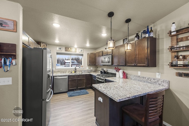 kitchen with sink, appliances with stainless steel finishes, dark brown cabinets, a textured ceiling, and kitchen peninsula