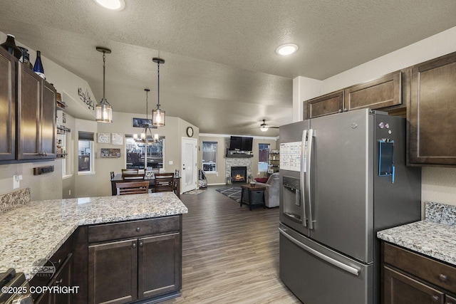 kitchen featuring a fireplace, decorative light fixtures, stainless steel fridge, dark brown cabinetry, and light hardwood / wood-style flooring