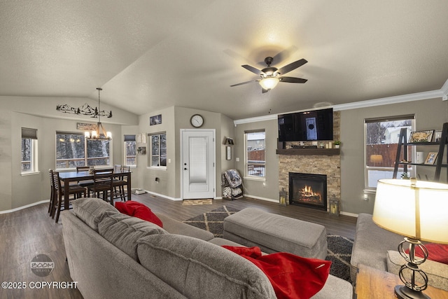 living room with lofted ceiling, hardwood / wood-style floors, a fireplace, a textured ceiling, and ceiling fan with notable chandelier