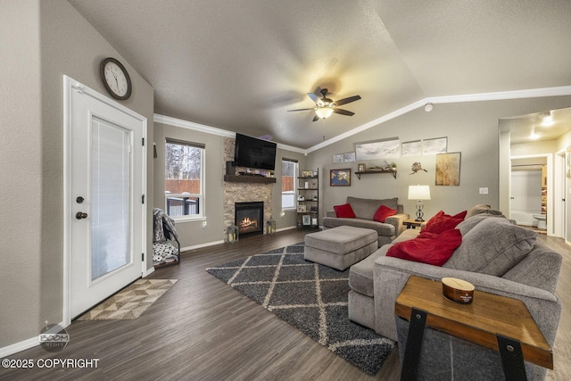 living room with dark wood-type flooring, ceiling fan, a fireplace, ornamental molding, and vaulted ceiling