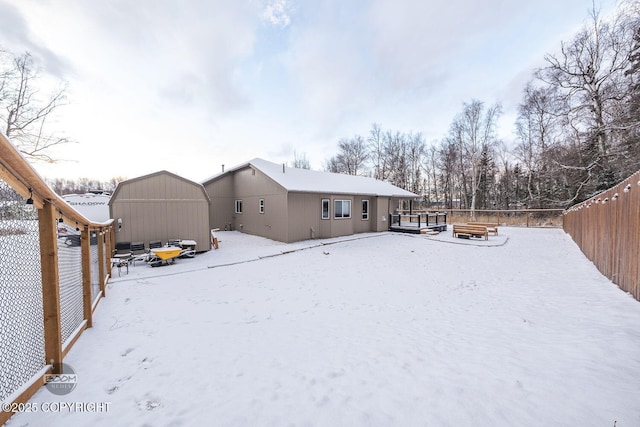 snow covered rear of property with a storage shed