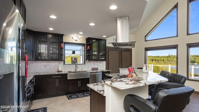 kitchen featuring sink, a center island, island exhaust hood, stainless steel appliances, and light stone countertops