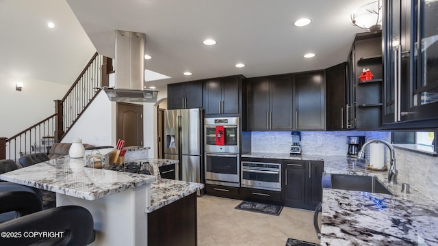 kitchen with sink, a kitchen island, stainless steel appliances, a kitchen breakfast bar, and island exhaust hood