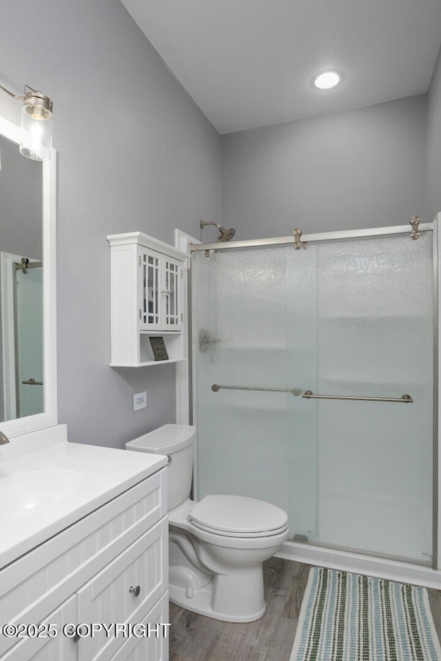 bathroom with hardwood / wood-style flooring, vanity, an enclosed shower, and toilet