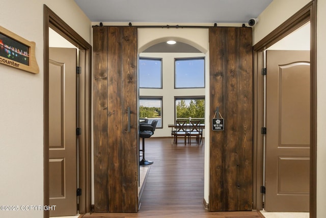 corridor with dark hardwood / wood-style floors and a barn door