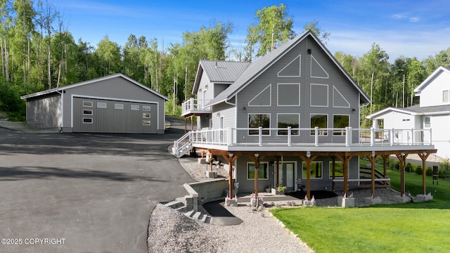 rear view of property with a garage, an outdoor structure, a deck, and a lawn