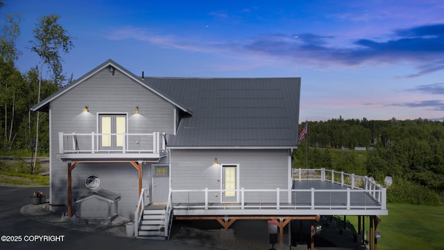 back house at dusk with french doors and a balcony