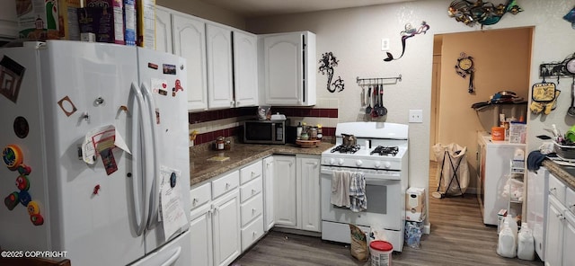 kitchen with white appliances, white cabinetry, dark stone countertops, dark hardwood / wood-style flooring, and washer / clothes dryer