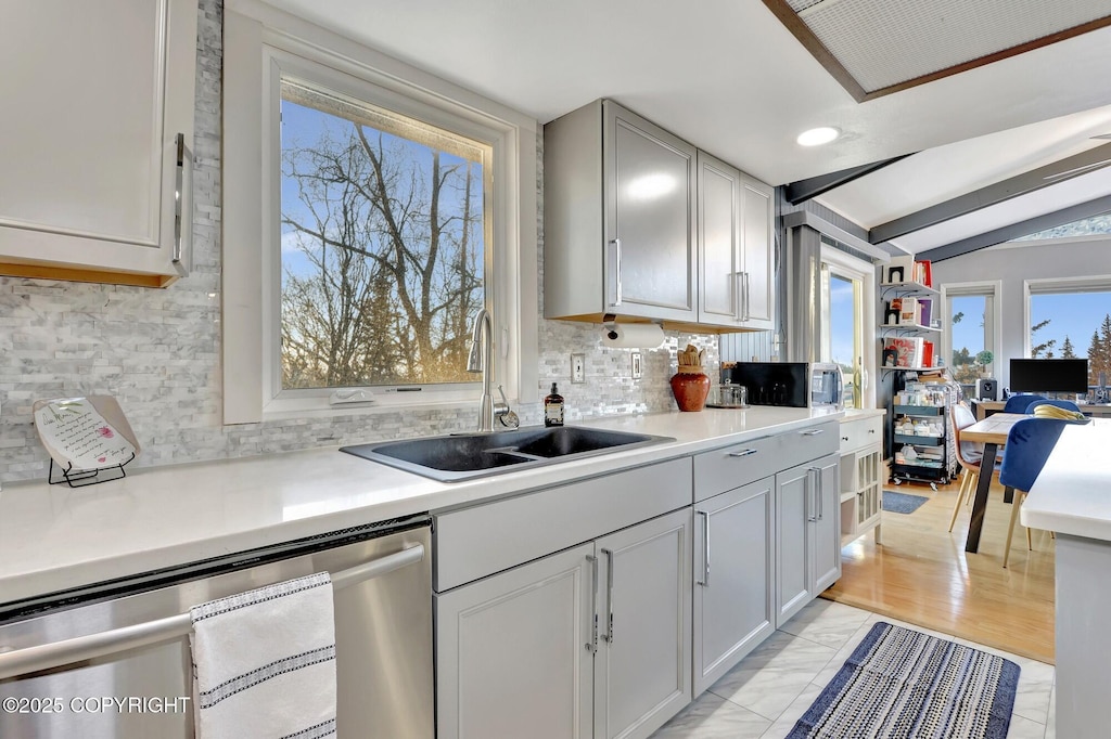 kitchen featuring tasteful backsplash, dishwasher, sink, and vaulted ceiling with beams