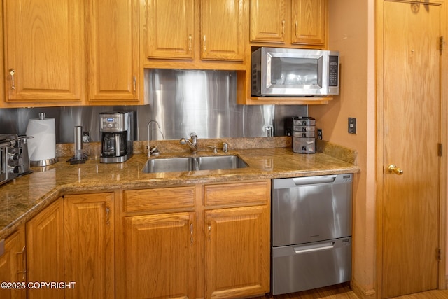 kitchen featuring stone counters, dishwasher, and sink