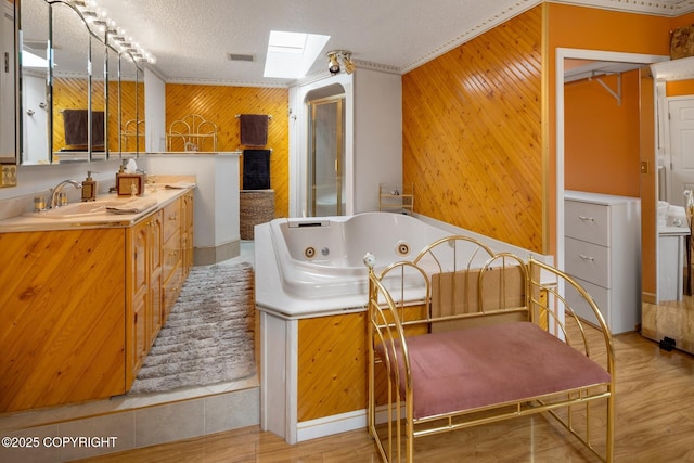 bathroom featuring a skylight, a bathtub, a textured ceiling, and wood walls