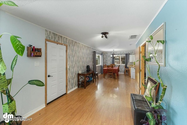 interior space featuring ornamental molding, light hardwood / wood-style flooring, and a textured ceiling